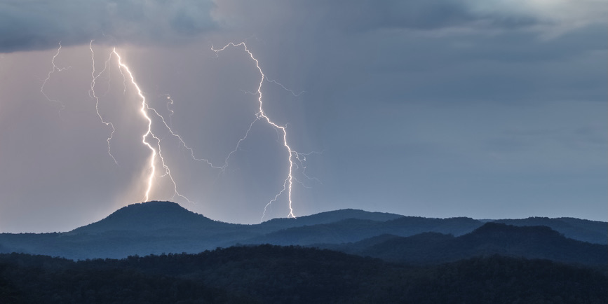 Looking over the Wollombi valley towards the Watagan mountains with Mount Warrawolong taking a direct hit of lightning, New South Wales, Australia.